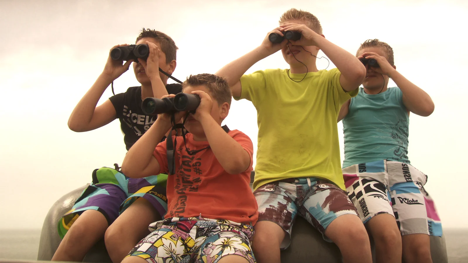 Four boys look through binoculars together in The Hideout.