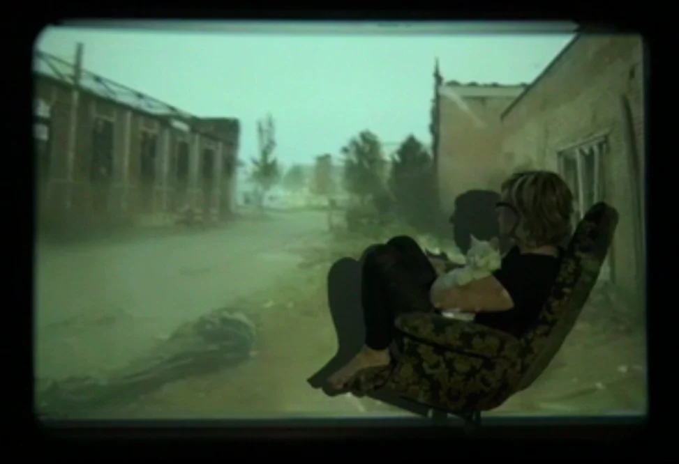 A person sits in an armchair in front of a projected street scene in My Enschede.